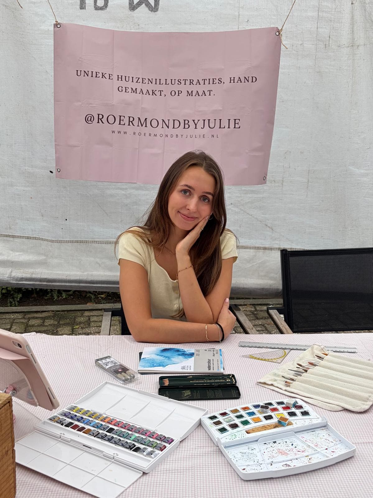 Julie achter haar kraam met huizenillustraties